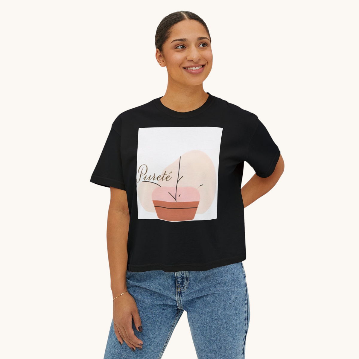 A woman wearing a black PURETE boxy cotton t-shirt with an abstract plant graphic, paired with blue denim jeans.