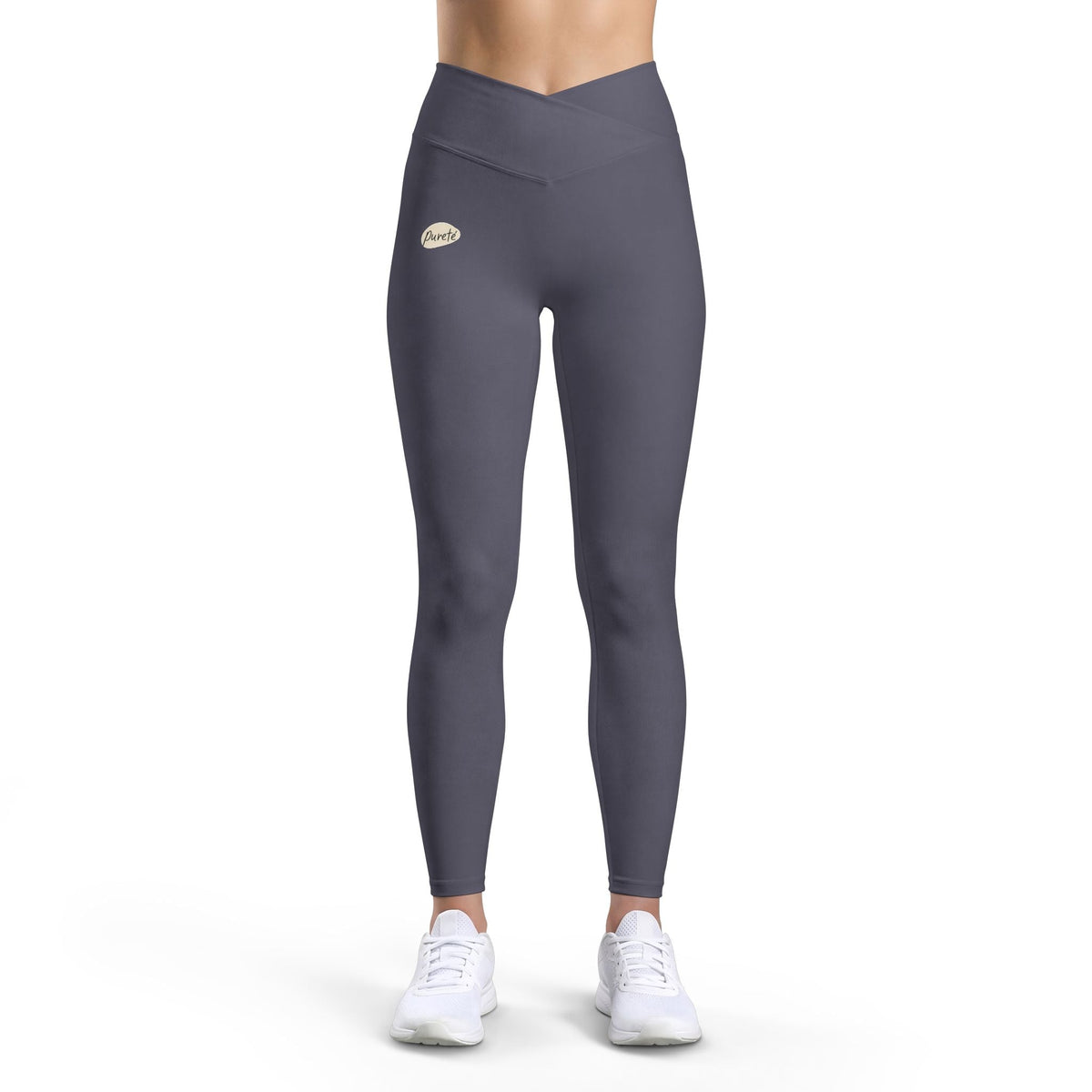 PURETE high-waist charcoal grey yoga leggings with a v-cut waistband and subtle logo, worn by a model in white sneakers.
