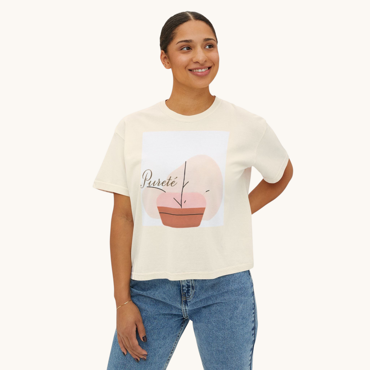 A woman wearing a PURETE cream-colored oversized boxy cotton t-shirt with a minimalist abstract plant graphic.