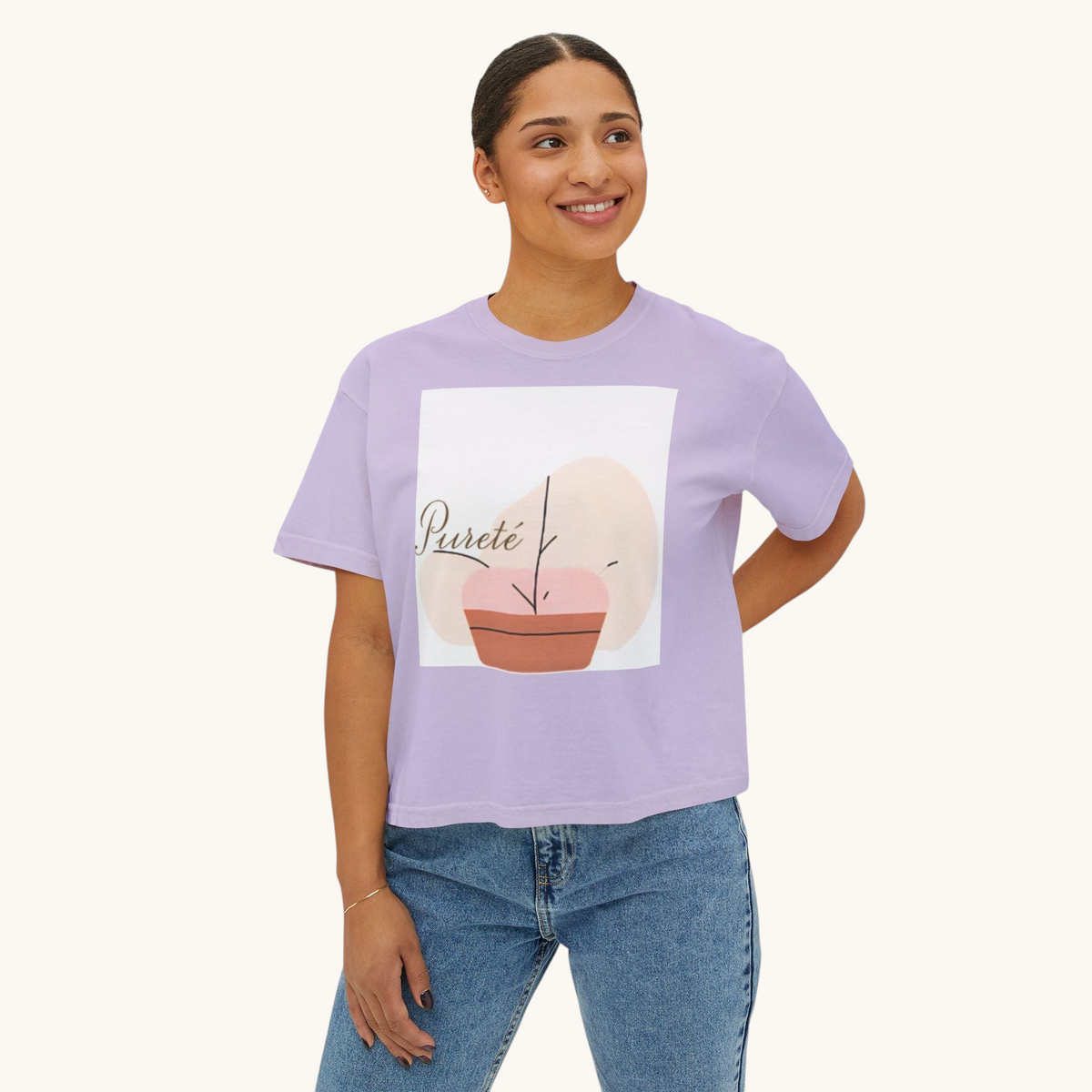 Woman wearing a PURETE lavender boxy cotton t-shirt with an abstract plant graphic print and blue denim jeans.