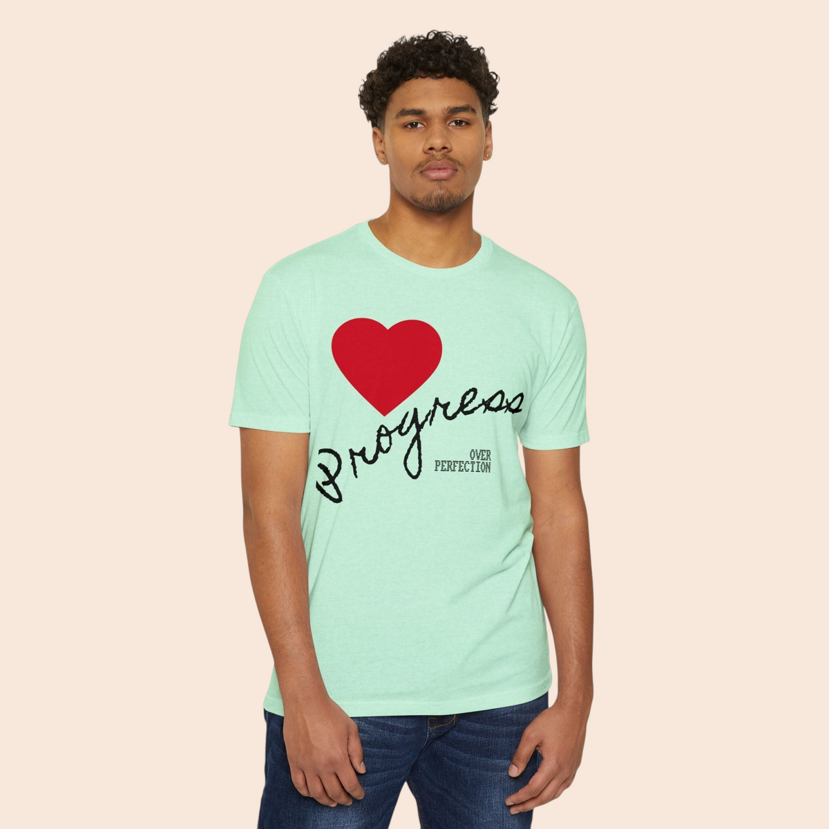 A man wearing a PURETE mint green cotton-blend t-shirt featuring a red heart and Progress Over Perfection graphic.