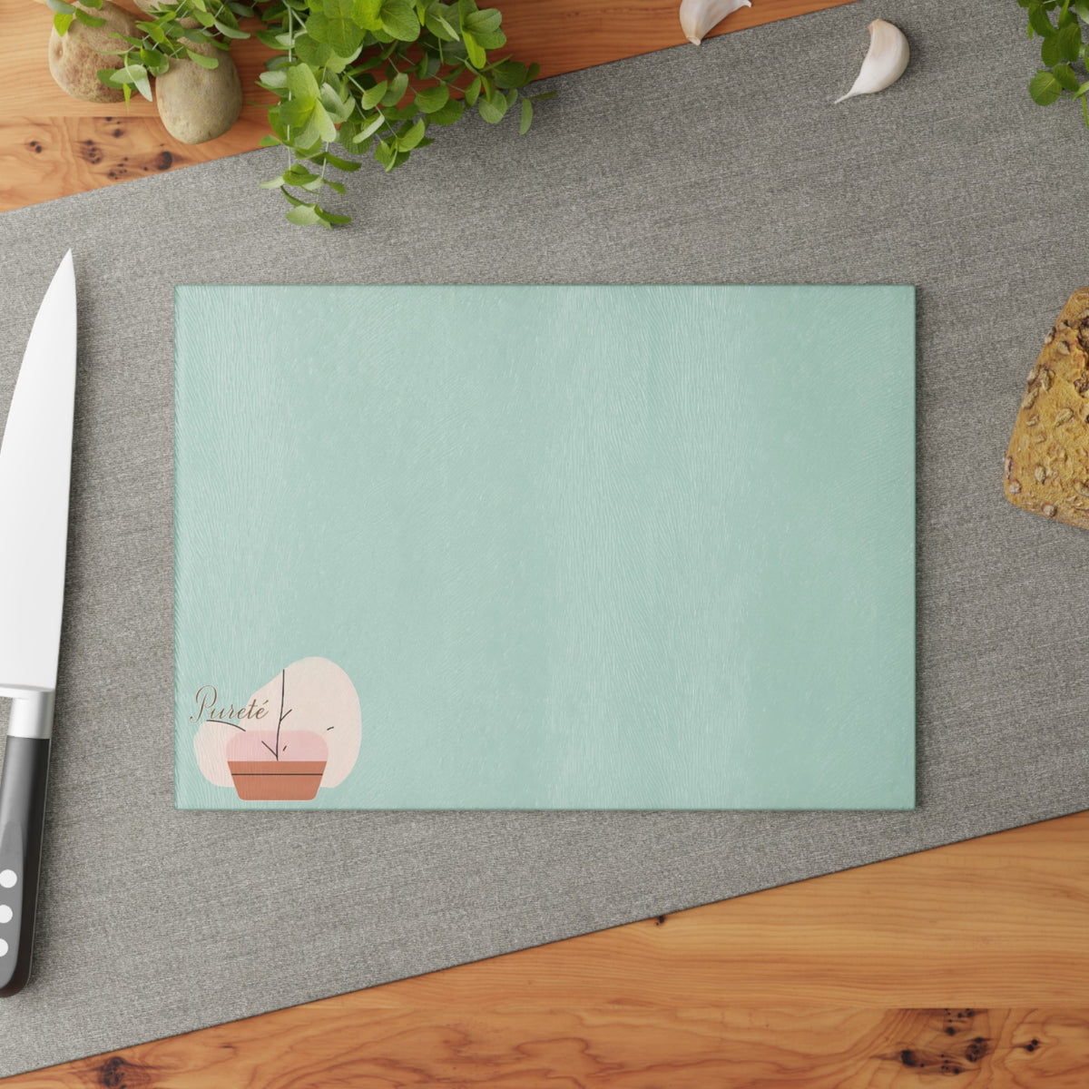 PURETE tempered glass cutting board with a textured mint green surface and minimalist potted plant logo design.