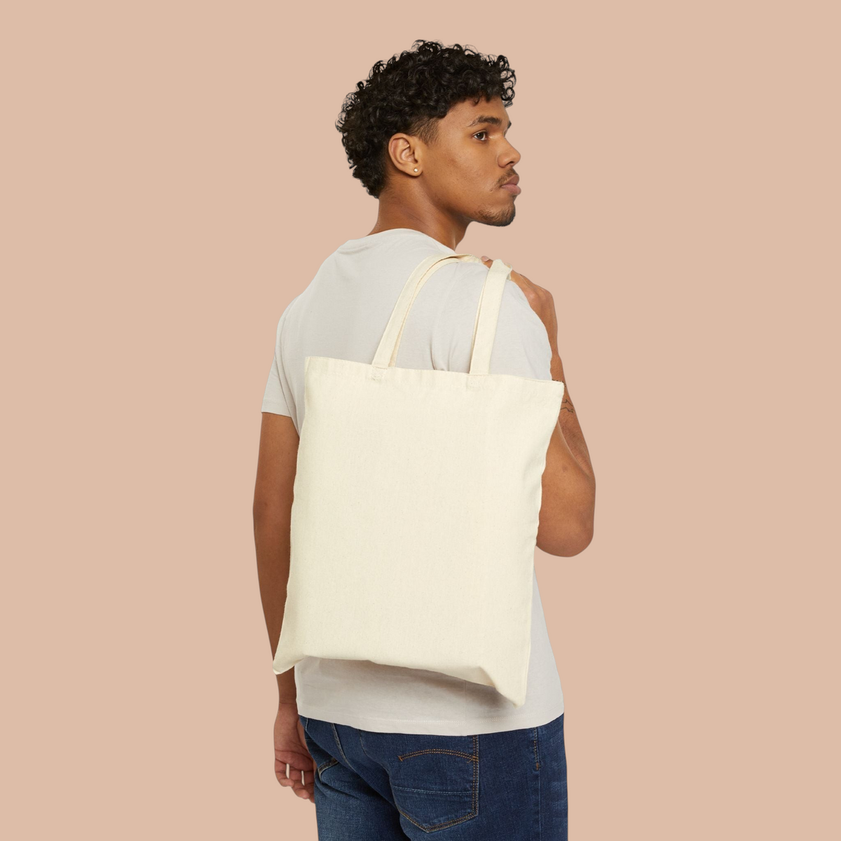 A man wearing a natural cotton canvas tote bag from PURETE over his shoulder against a white background.