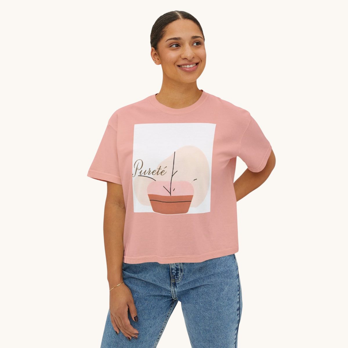 A woman wearing a PURETE pink boxy oversized cotton t-shirt with a minimalist abstract plant graphic, paired with jeans.