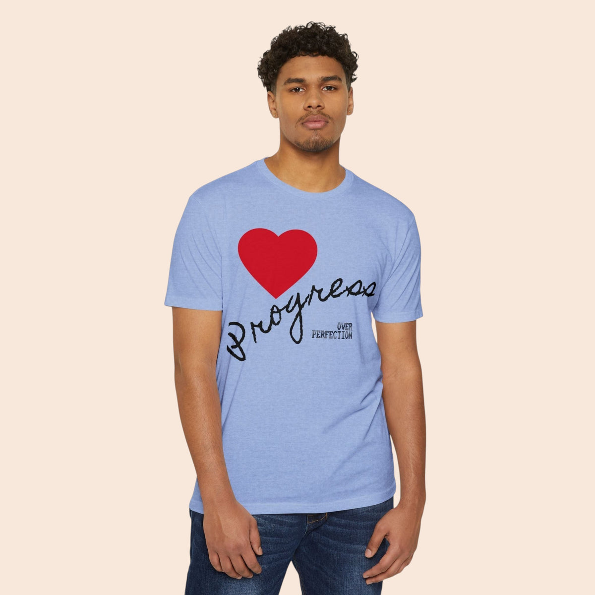 A man wearing a PURETE light blue cotton-blend t-shirt featuring a red heart and Progress Over Perfection graphic.