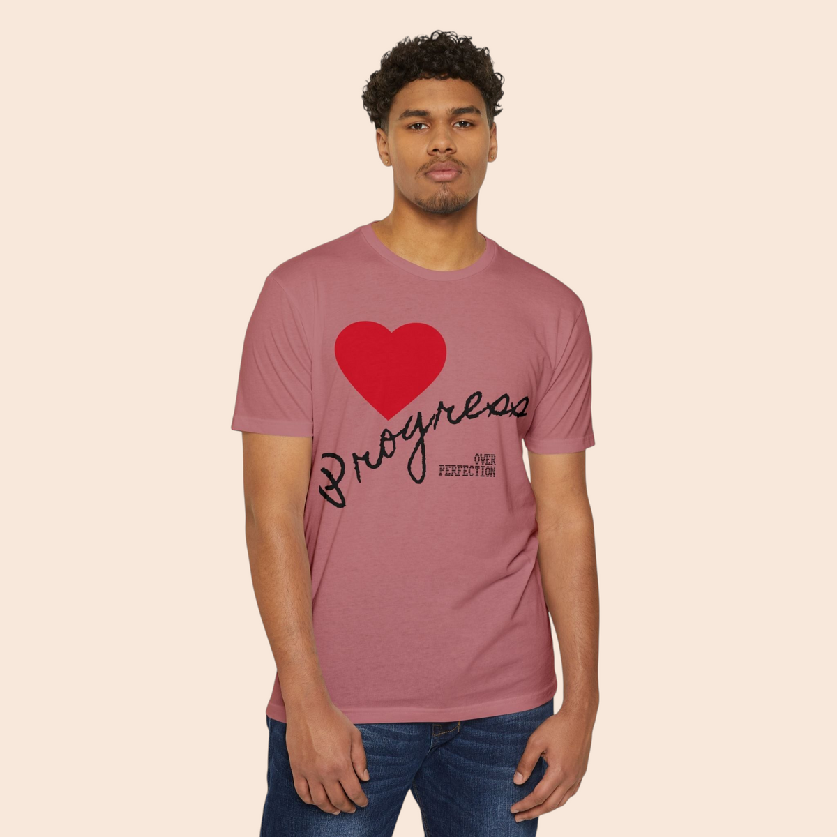 A man wearing a PURETE mauve cotton-blend t-shirt featuring a red heart and Progress Over Perfection graphic.
