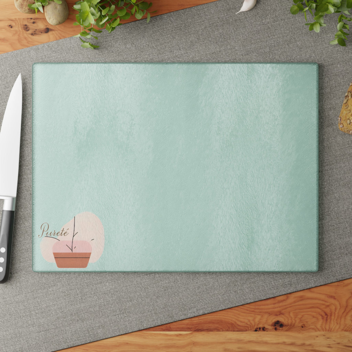 PURETE tempered glass cutting board with a textured mint green surface and a small potted plant graphic.