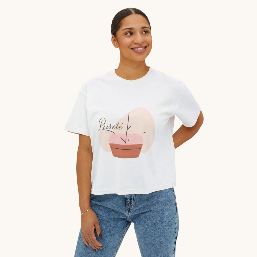 A woman wearing a white PURETE boxy cotton t-shirt with a minimalist plant graphic, paired with blue denim jeans.