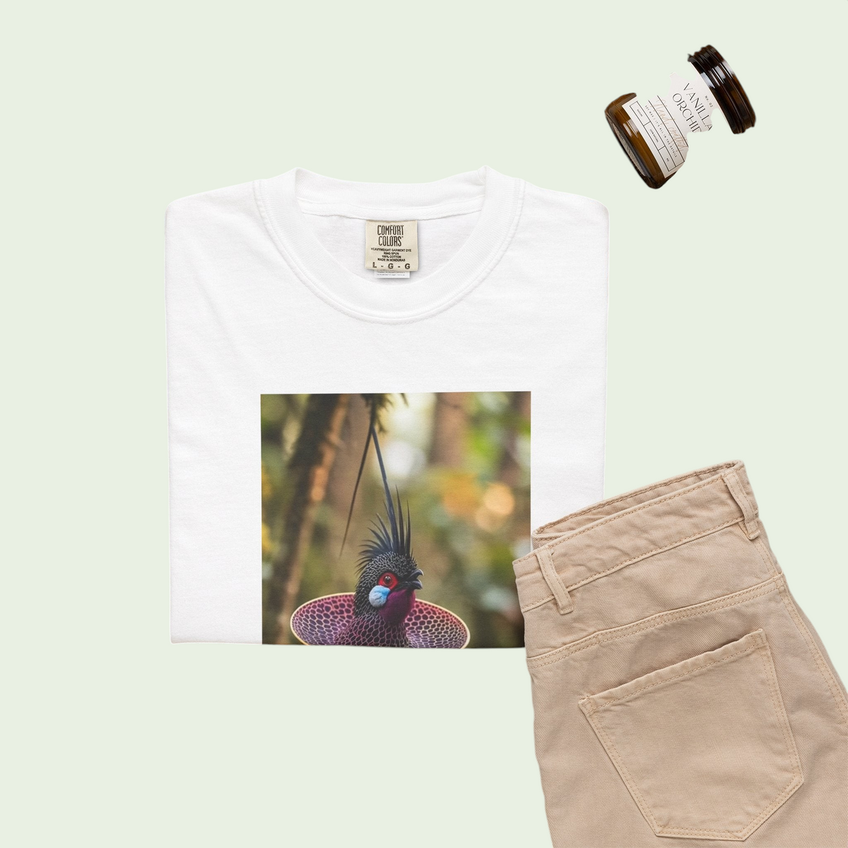 PURETE white heavyweight cotton t-shirt featuring a tropical bird graphic, styled with beige trousers and a candle.