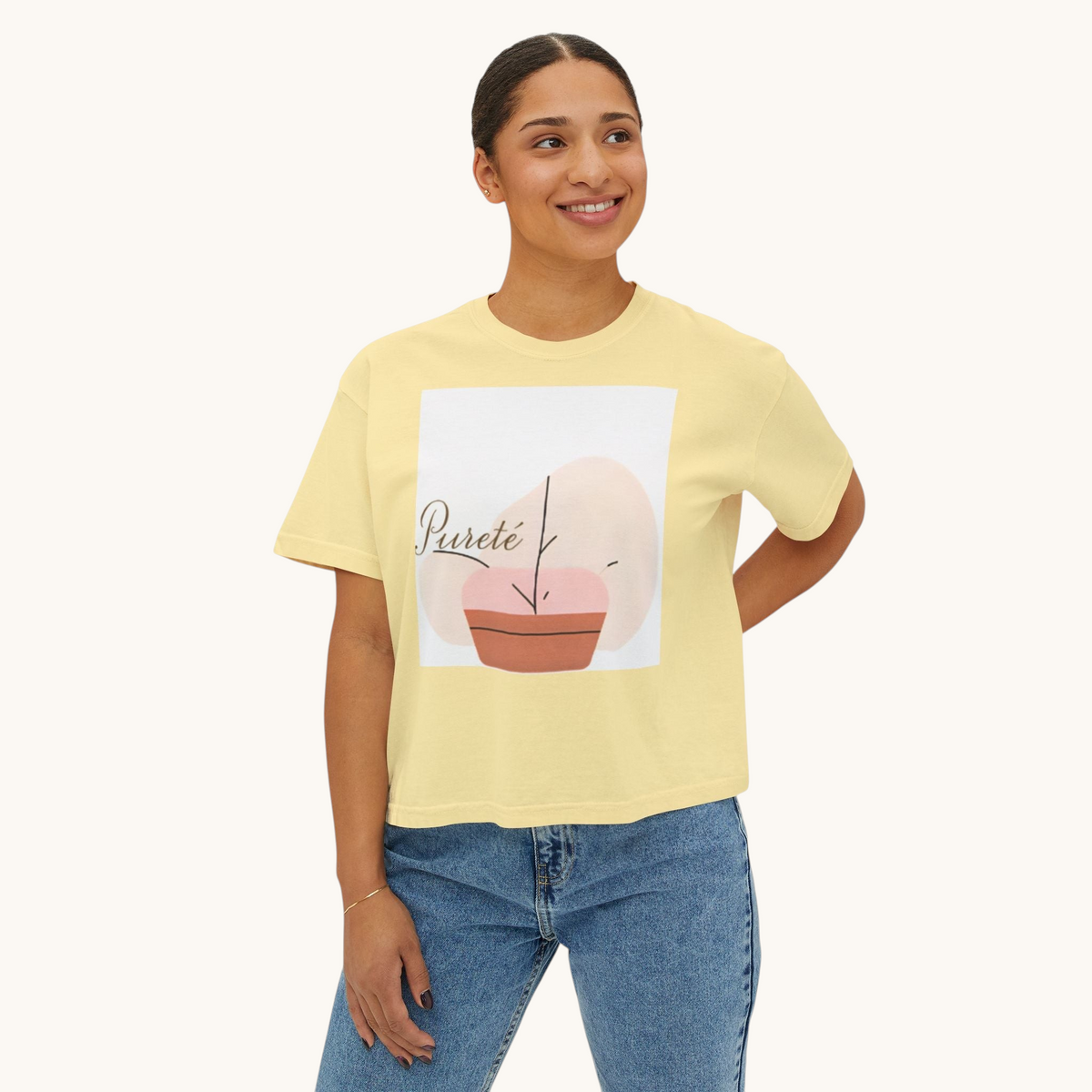 A woman wearing a PURETE yellow boxy cotton t-shirt with an abstract plant graphic, paired with blue jeans.